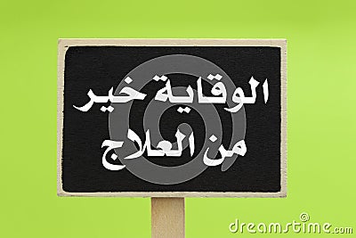Prevention Is Better Than Cure written in Arabic on a chalkboard against green background Stock Photo